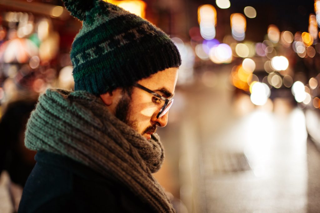 close up of man with glasses looking down during winter night