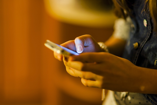 Teenager looking at mobile phone in dim light.